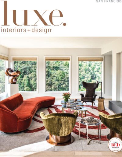 Stylish modern living room with large windows, elegant furniture, and a lush forest view.
