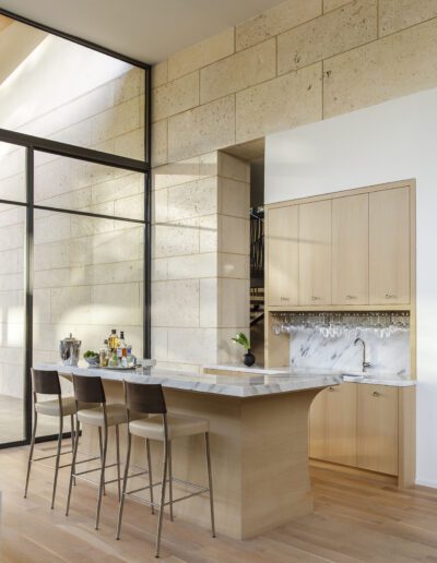 Modern kitchen interior with stone walls, wood cabinets, and a breakfast bar with stools.
