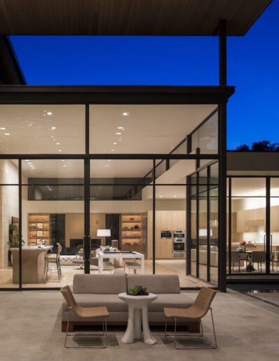 Modern home interior visible through large glass windows at dusk.