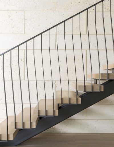 Modern staircase with wooden steps, metal railing, and a textured wall.