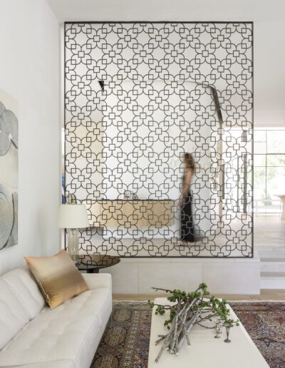 A spacious living room with modern decor and a large decorative partition, behind which a person is partially visible.